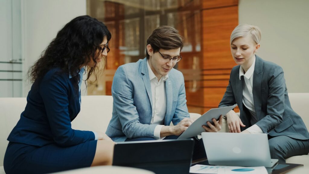 YourInsight Leistungen Team Drei Fachleute arbeiten gemeinsam mit Laptop, Tablet und Unterlagen